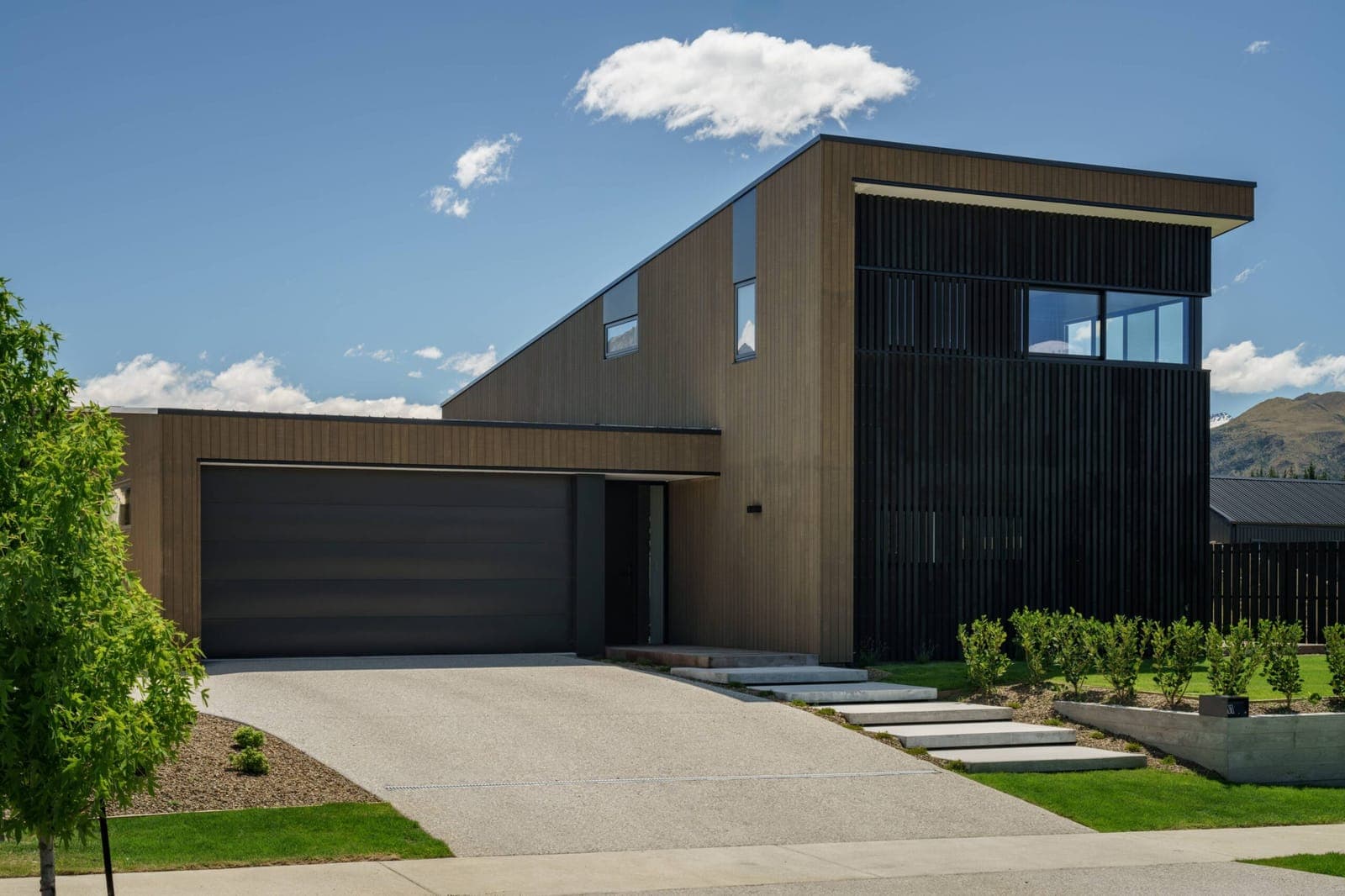 Cedar-clad house with a black batten screen, ranges behind